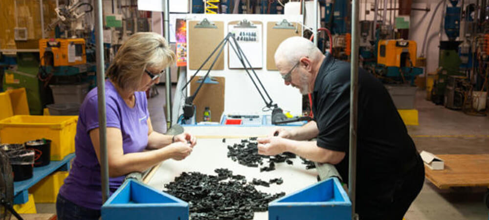 Two people work at a sorting table on the plant floor.