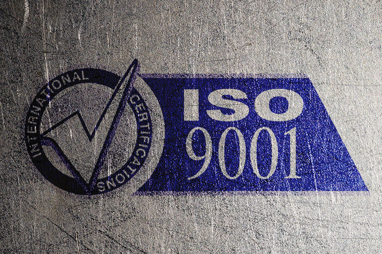 A blue ISO 9001 logo on a metal background