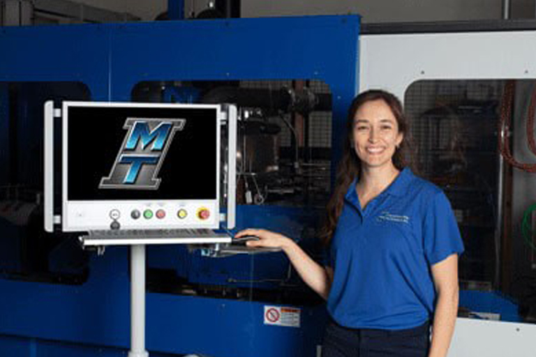 MTI’s Constanza Lengerich in front of a Low Force Friction Welding Machine for R&D.