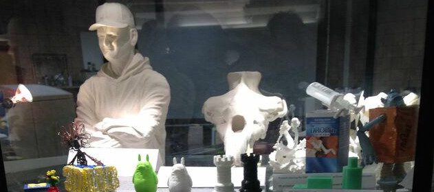 picture of examples of 3D art- a 3D printed Man with his arms crossed with hat, chess figurines, other various 3D prints