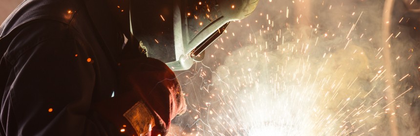 close up industrial worker with welding shield on welding, sparks flying