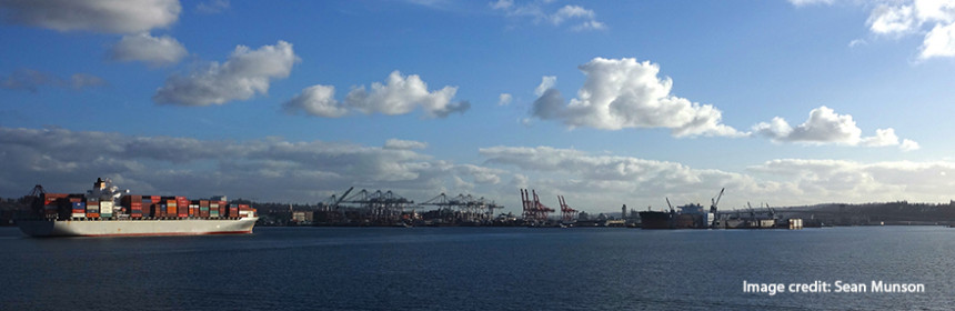 photo of a loaded container ship on the water, blue skies and clouds in the background