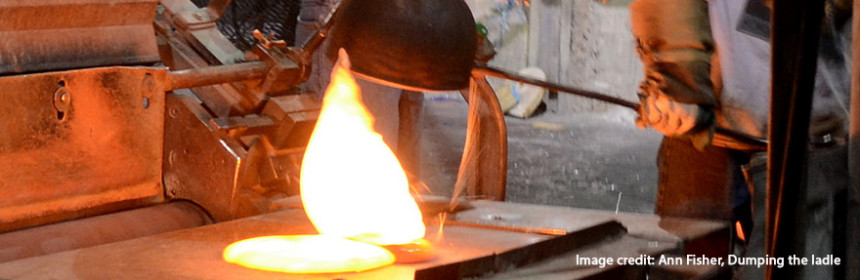 man in protective gear working with melted metals in foundry