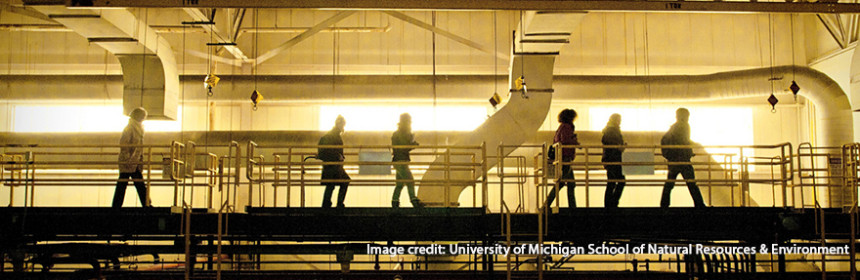 students walking an upper walkway in manufacturing plant