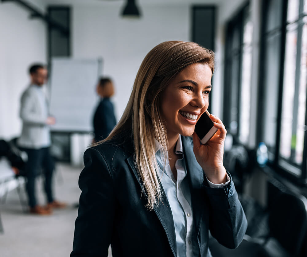 Portrait of a smiling blonde businesswoman talking on a phone during the break from a meeting.