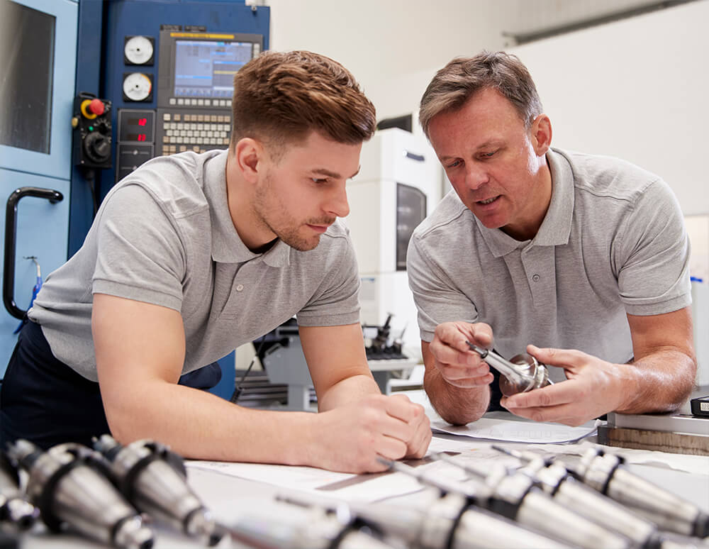 Engineer Showing Apprentice How To Measure CAD Drawings