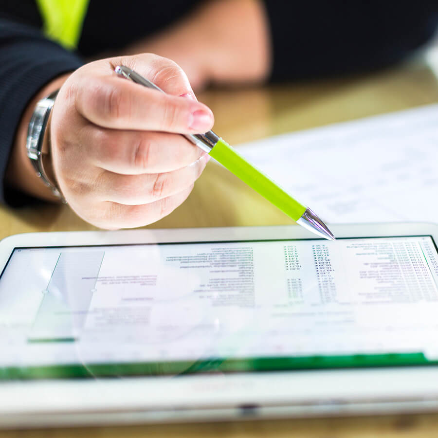 A person reviews information on a tablet computer using a pen to keep place